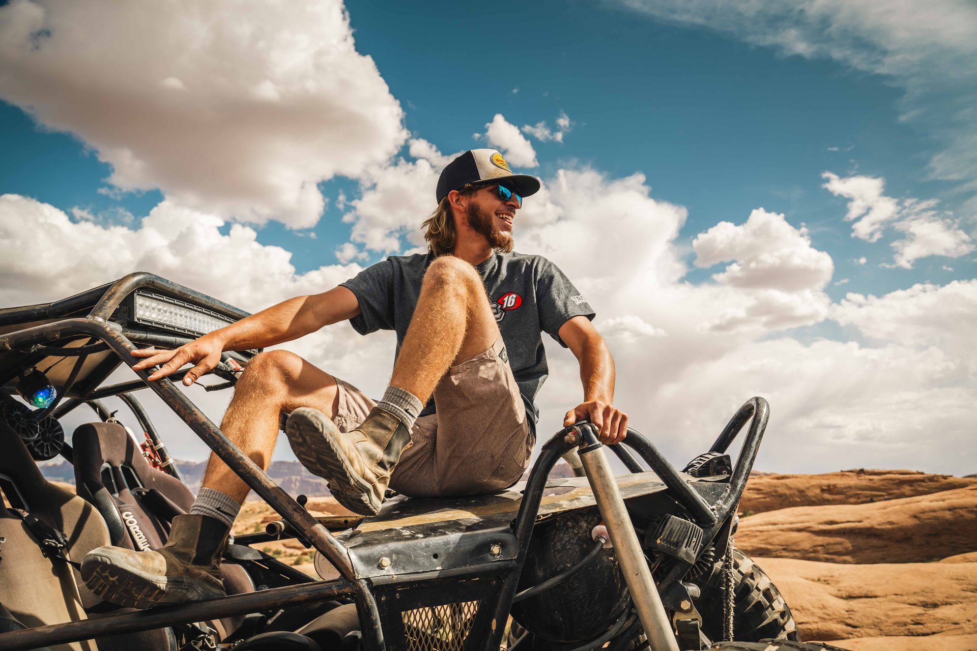 Driver standing up in his buggy under desert clouds