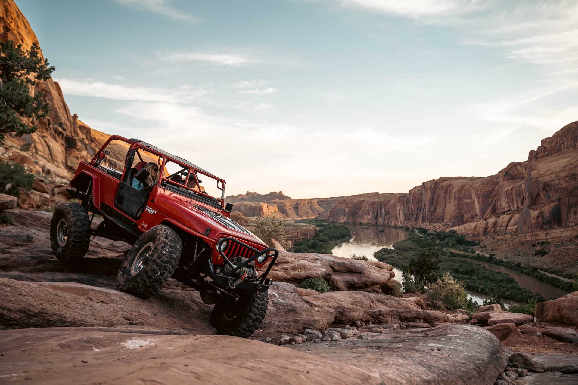 Red Jeep on a ledge above a river canyon